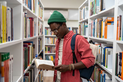 Passionate reader student african american guy choosing research textbooks in university library.