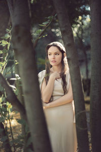 Thoughtful fairy elf young woman standing by trees