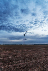 Wind turbines on field against sky