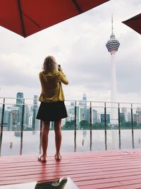 Rear view of woman standing at infinity pool 