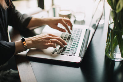 Midsection of woman using laptop on desk