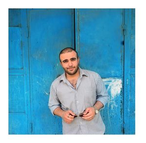 Portrait of young man standing against blue door