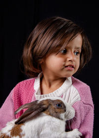 Close-up portrait of cute girl against black background