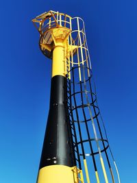 Low angle view of yellow tower against clear blue sky