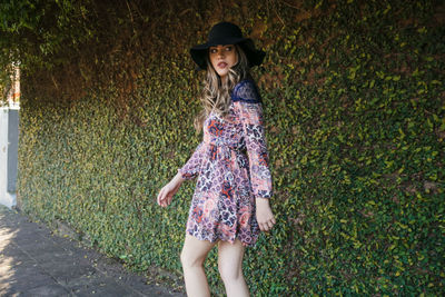 Woman wearing hat standing against plants