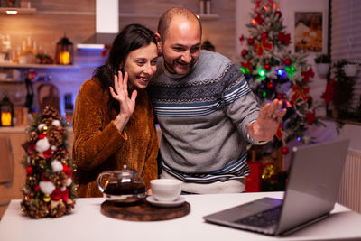 Smiling man and woman talking on video call at home