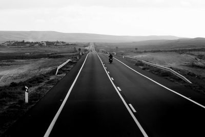 Motorcyclist on road leading towards mountains