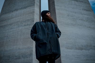 Low angle view of woman in warm clothing standing against wall