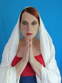 Portrait of young woman against blue background