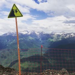 Road sign by mountain against sky