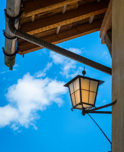 Low angle view of lamp hanging by building against sky