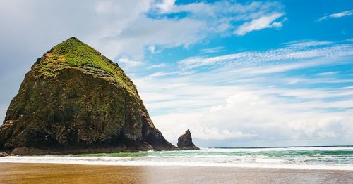 Rock formation at beach against sky