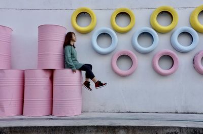 Side view of woman standing against pink wall