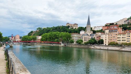 River by buildings in city against sky