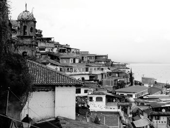 Houses by sea against sky in city