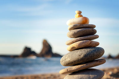 Stack of stones at beach against sky