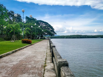 Footpath by lake against sky