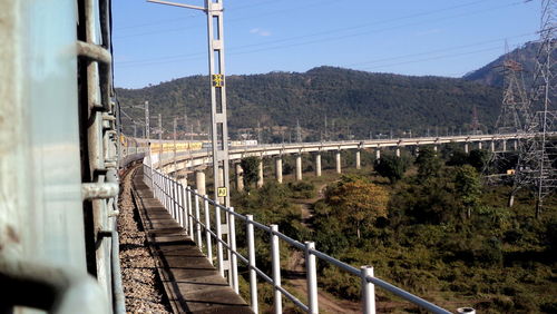 Train over bridge by mountain against sky