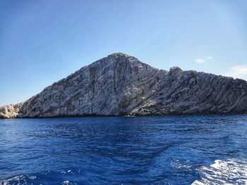 Scenic view of sea and mountains against clear blue sky