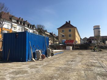 Road by buildings against blue sky