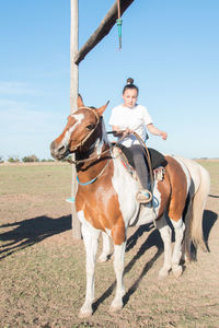 Girl sitting on horse against sky
