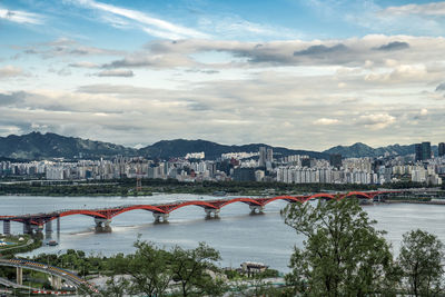 Bridge over river in city against sky