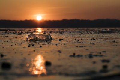 Surface level of wet puddle on beach during sunset