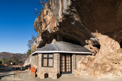 Built structure on rock by building against clear sky