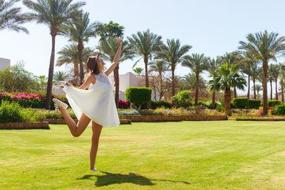 Woman standing by palm trees against sky