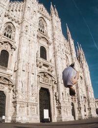 Low angle view of man jumping against milan cathedral