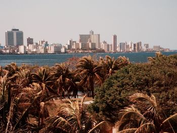 Cityscape by sea against clear sky