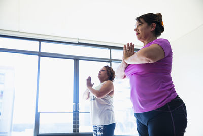 Low angle view of friends with hands clasped exercising in yoga studio