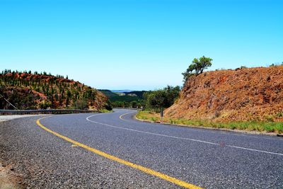 Road by trees against clear sky