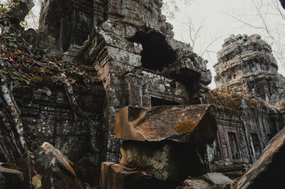 Low angle view of cross on rock against trees