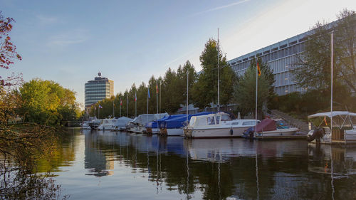 Sailboats moored in lake against sky in city