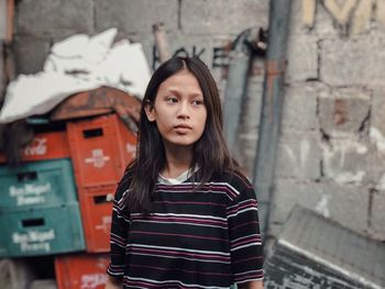 Portrait of beautiful young woman standing against brick wall