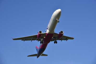 Low angle view of airplane against clear blue sky