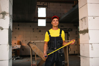 Portrait of young man standing against wall