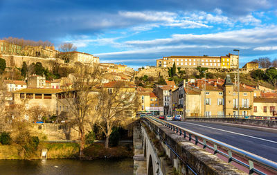 Arch bridge over river amidst buildings against sky