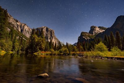 Scenic view of lake and mountains against clear sky at night