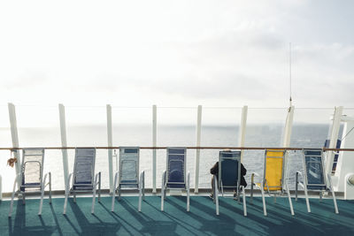 Chairs by swimming pool against sky