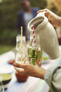 Cropped image of woman serving mojito in bottle at summer party