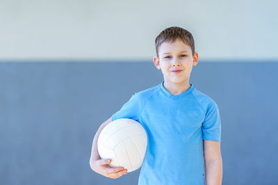 Portrait of smiling boy standing against blue wall