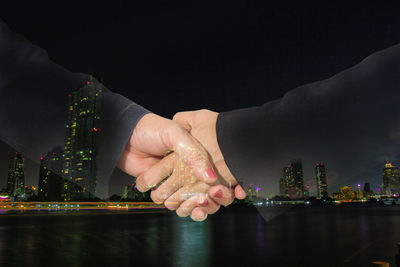 Close-up of hand touching hands against sky at night