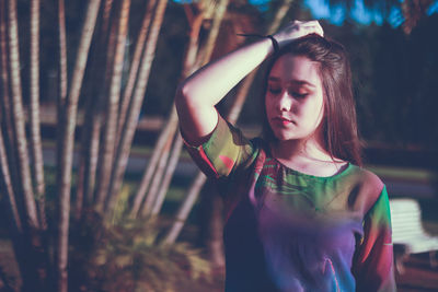 Beautiful woman standing by tree on field during sunny day