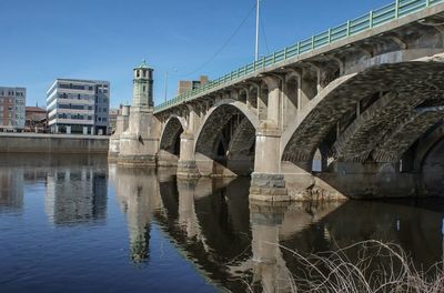 Reflection of bridge in water against clear blue sky