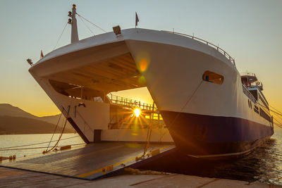 Ship moored at harbor against sky during sunset