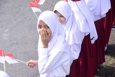 Portrait of schoolgirl wearing uniform while standing in row outdoors