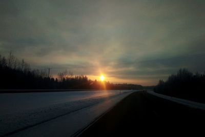 Road amidst silhouette landscape against sky during sunset