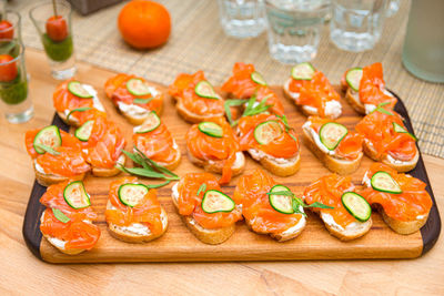 Appetizer canape with smoked salmon and cucumber with cream cheese spread on wooden board